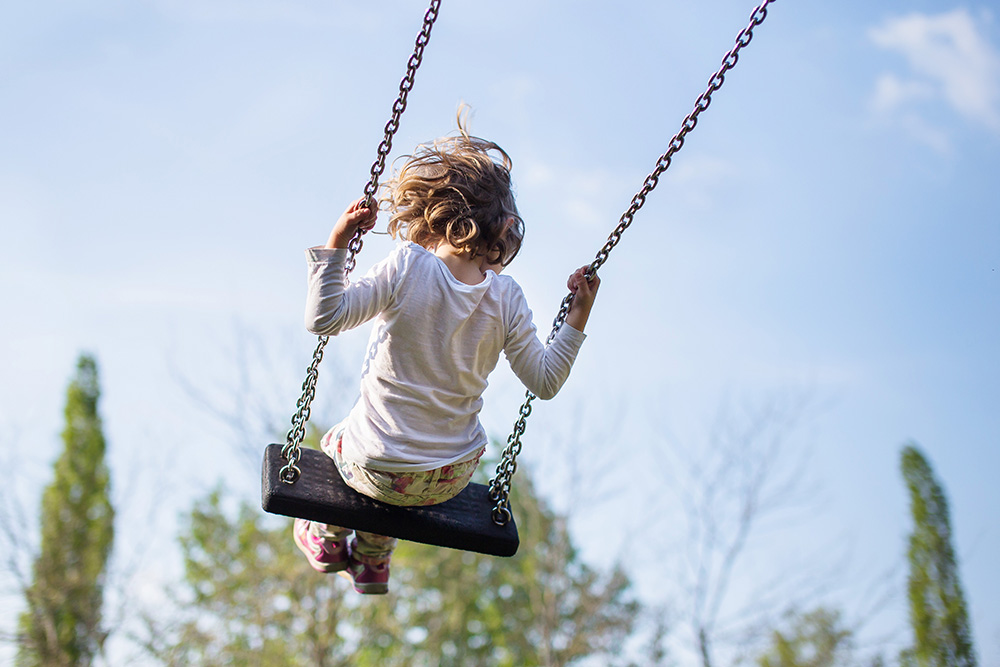 girl on swingset playground