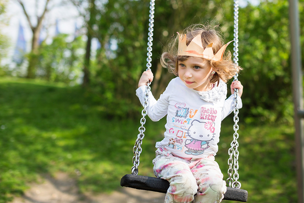 little girl with paper crown playing