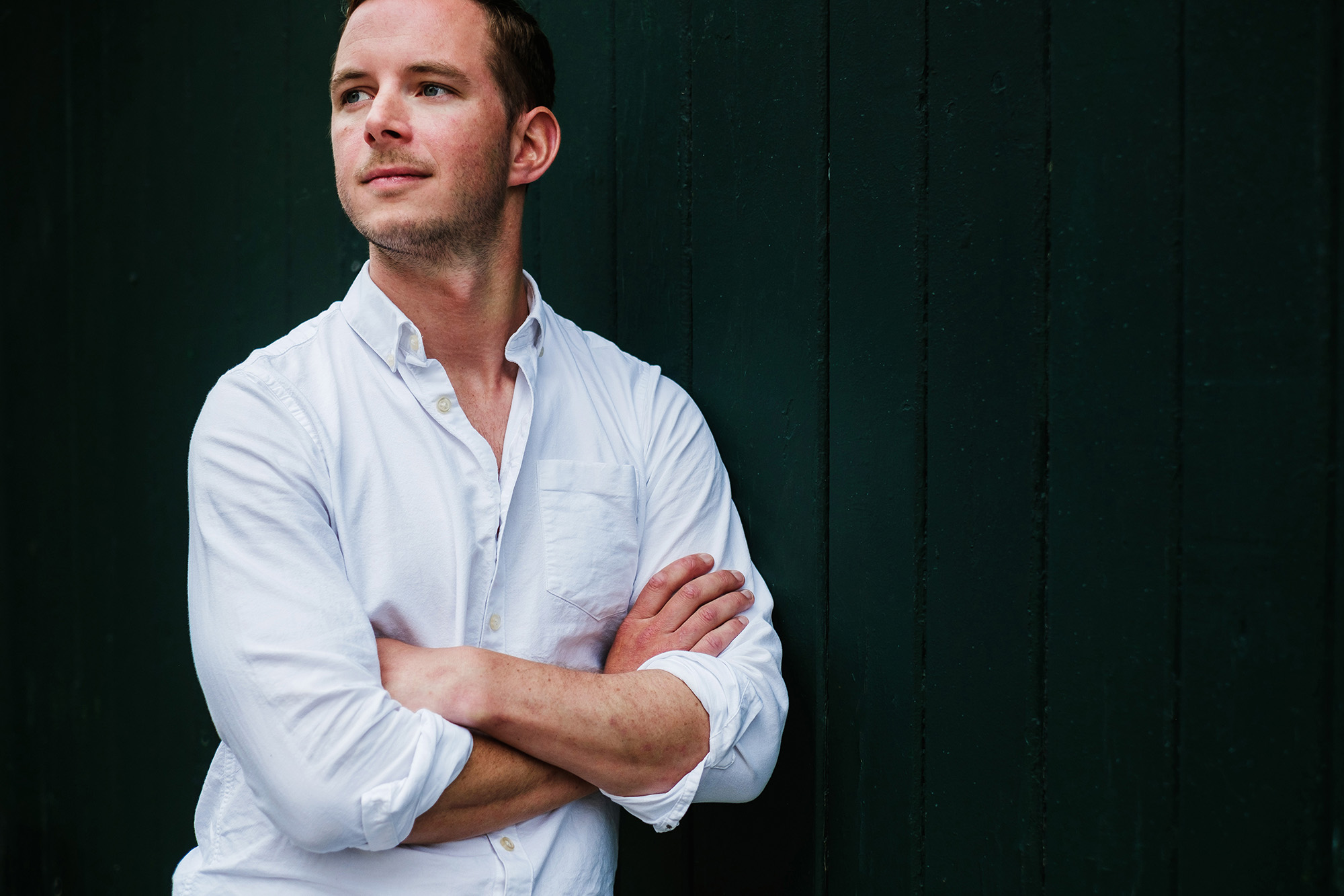 man crossed arms leaning against wall