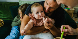 mum feeding baby with dad helping, documentary family photos