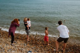 photographer photographing with a family on the beach in sussex